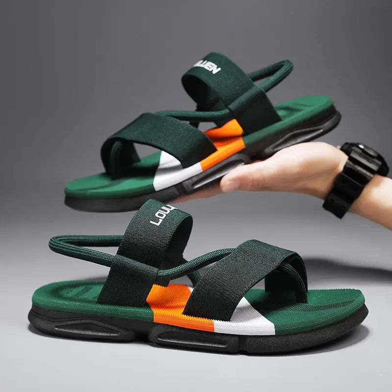 Men's dark green elasticated strap sandals by Louluen, featuring a bold multi-color sole stripe (orange, white, red) and a chunky black outsole, shown from a three-quarter angle with one sandal held by a hand.