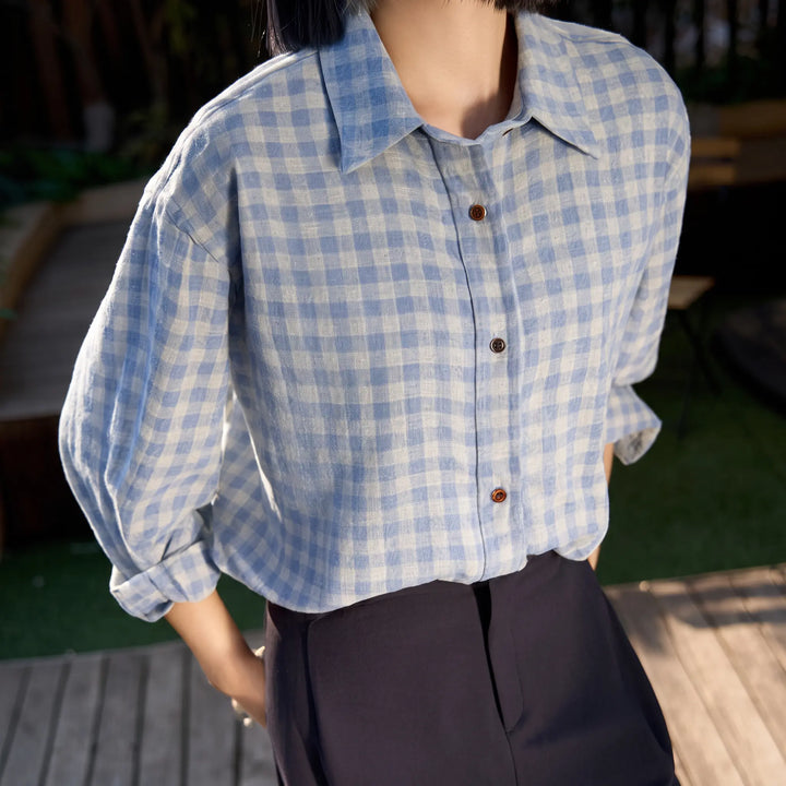 A woman models a relaxed-fit Aerium brushed cotton plaid shirt in blue and grey, featuring a POLO collar and button-down front, styled with dark trousers in an outdoor setting.