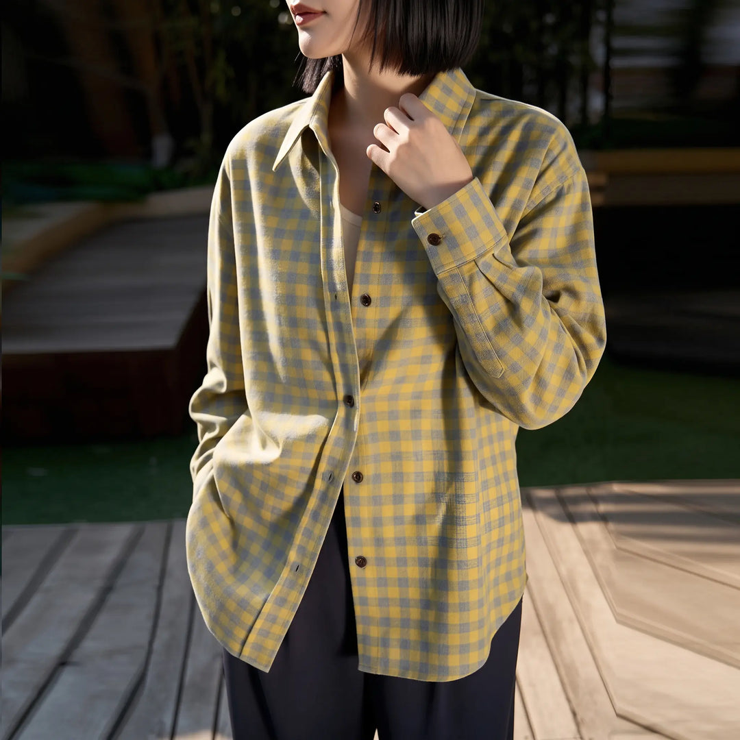 A woman wears a yellow and grey plaid brushed cotton shirt with a relaxed fit, styled outdoors on a wooden deck. The shirt features a POLO collar and button-down front.
