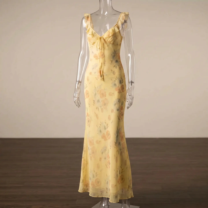 Aethelgard floral maxi dress in pale yellow with a plunging V-neck, ruffled trim, adjustable tie front, and mermaid hem. This elegant, sleeveless chiffon dress features a romantic floral print, ideal for summer evenings.