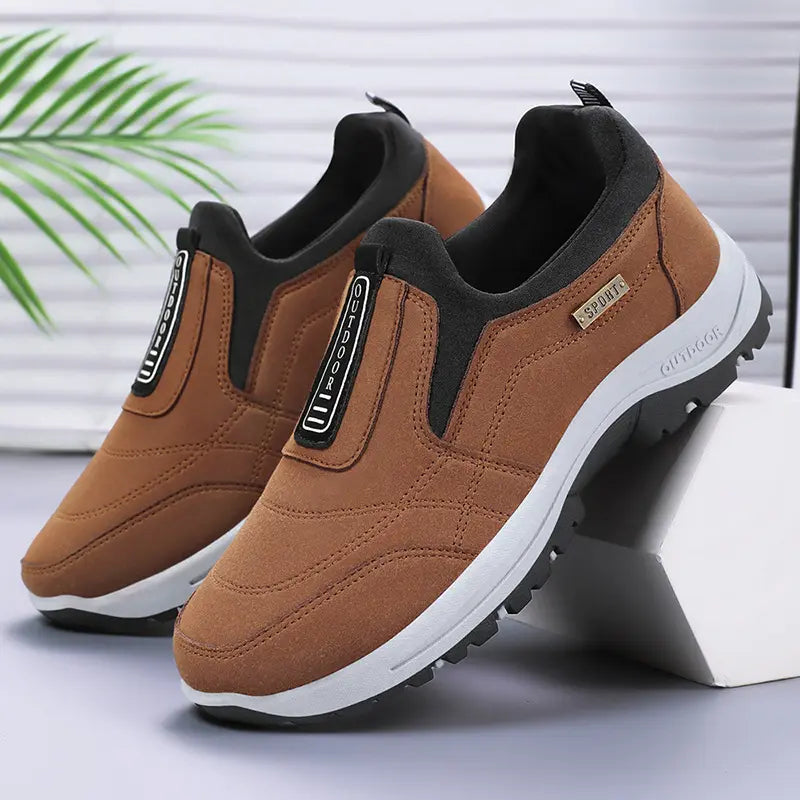 Aklos men's casual slip-on walking shoes in brown textile, featuring a white EVA midsole and black lugged rubber outsole, shown in a three-quarter view.