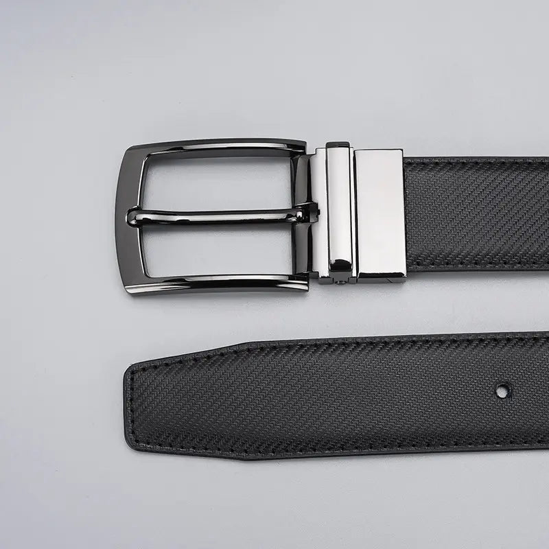 Close-up of a reversible textured black leather belt with a gunmetal grey rotating pin buckle, showcasing the intricate weave pattern and buckle mechanism.