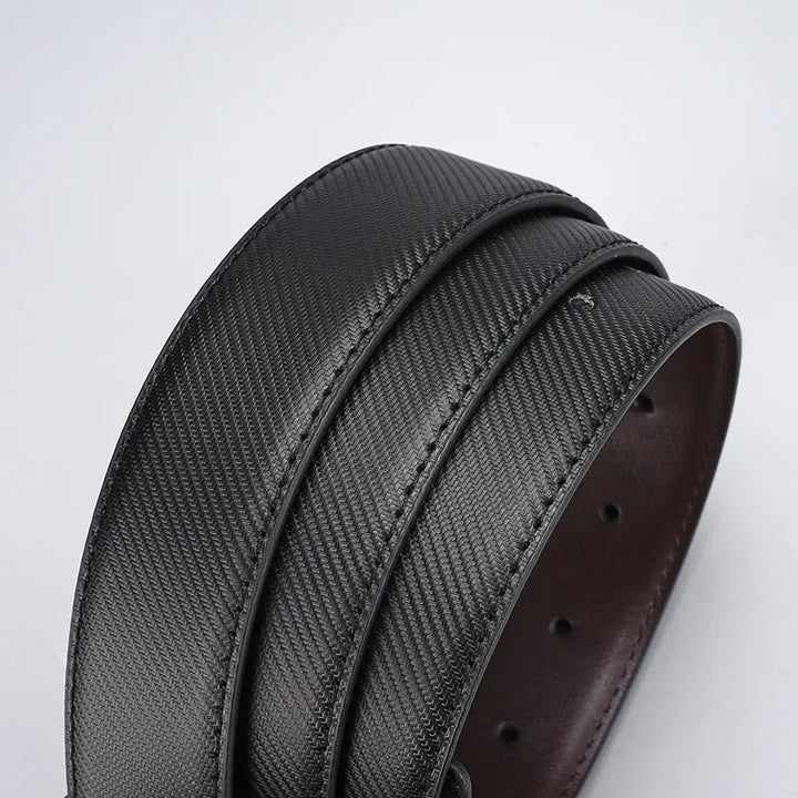 Close-up of a reversible black textured leather belt, showing fine carbon-fibre-like pattern and dark edge stitching. The smooth brown interior is partly visible.