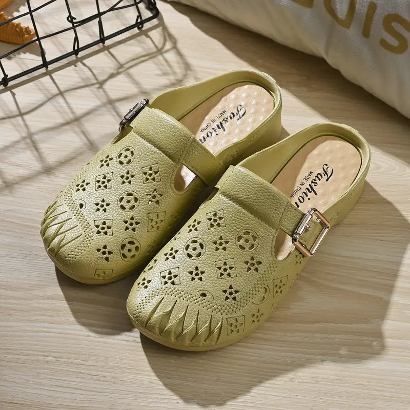 Pair of light khaki Azova textured synthetic mules with embossed geometric pattern, round pleated toe, and adjustable gold buckle strap, presented on a wooden surface.