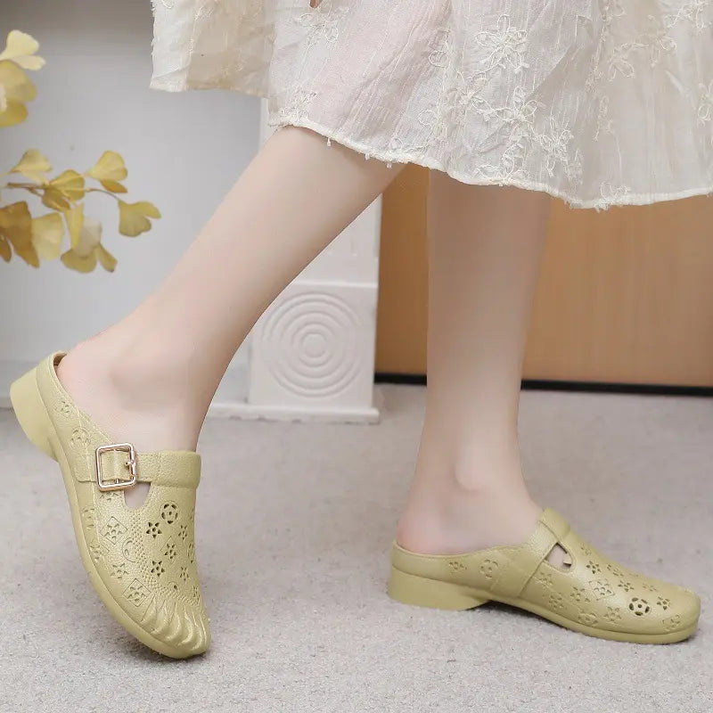 Model wearing textured beige slip-on mules with a gold-tone adjustable buckle strap and perforated detailing.