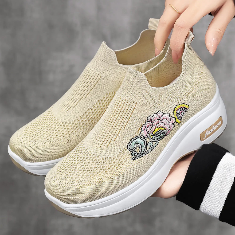 Kyzra women's beige knit slip-on sneakers featuring colorful floral embroidery on the side and a supportive white platform sole with embossed 'fashion' logo.