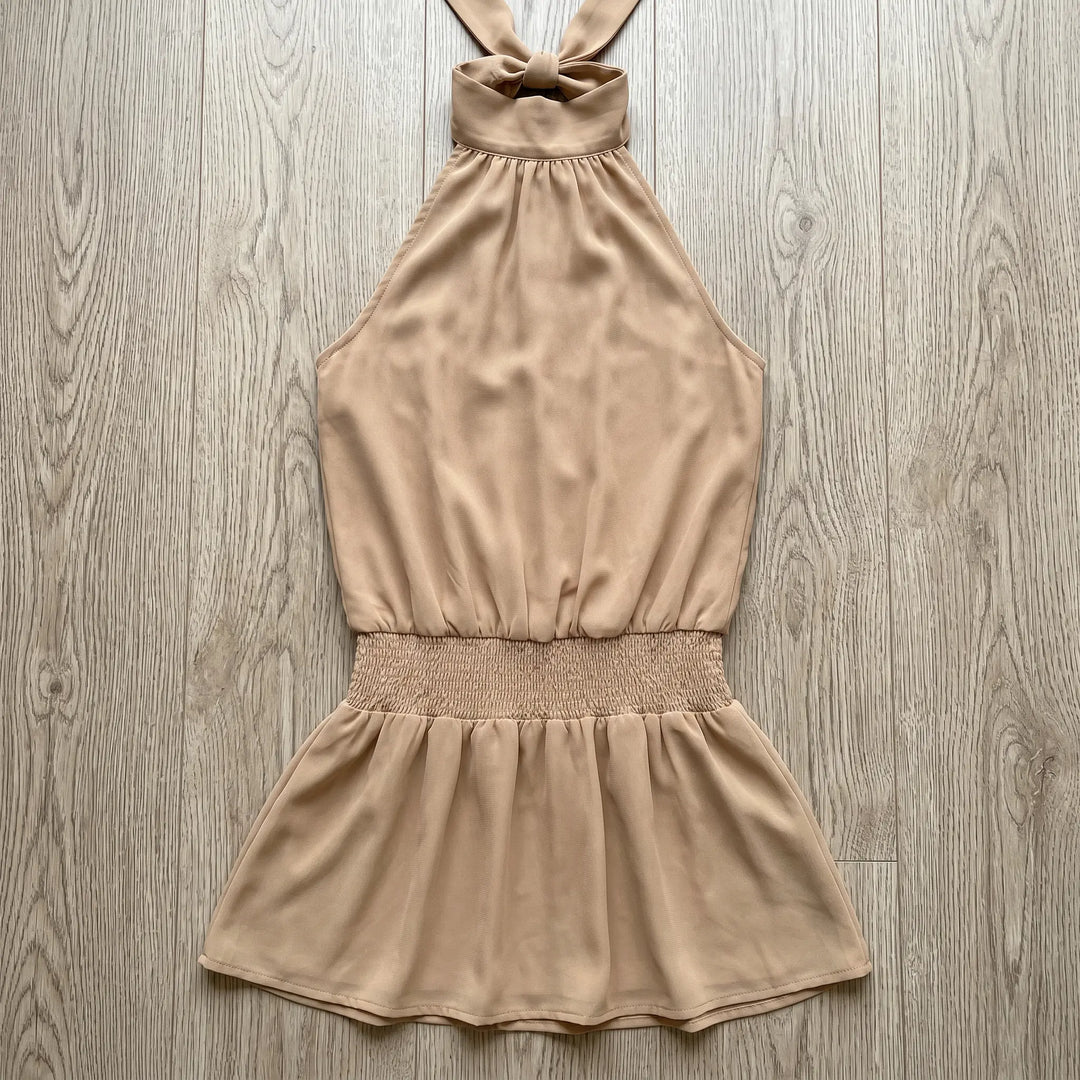 Soft beige polyester blend halter neck mini dress with a shirred elastic waistband and a flattering A-line skirt, laid flat for display.