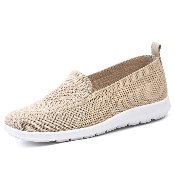 Beige breathable knit slip-on shoe with a subtle diamond weave pattern on the vamp and a clean white sole, shown from a three-quarter angle.