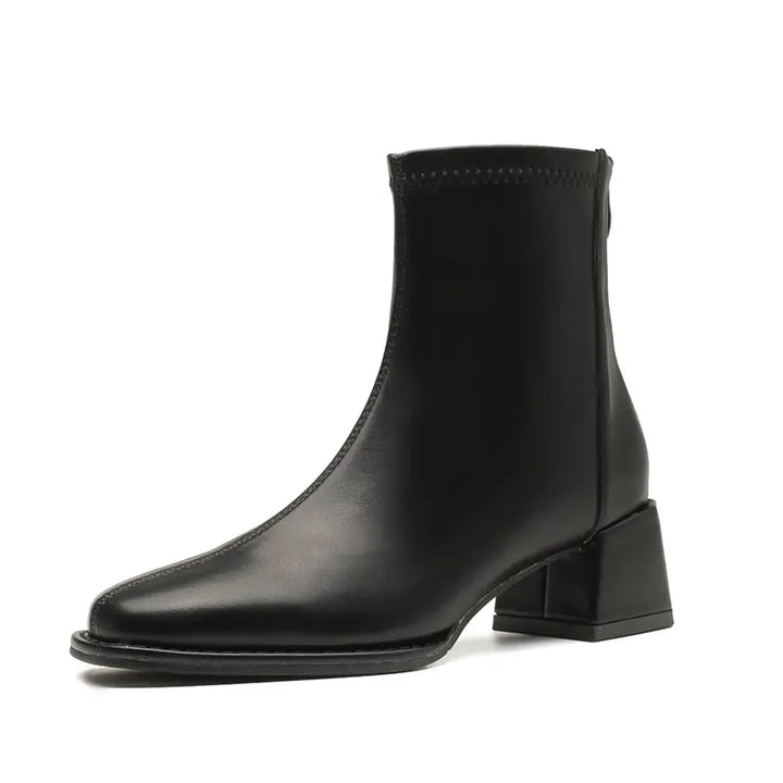 A black faux leather ankle boot with a square toe, chunky block heel, and a convenient back zipper, shown in a three-quarter studio view.