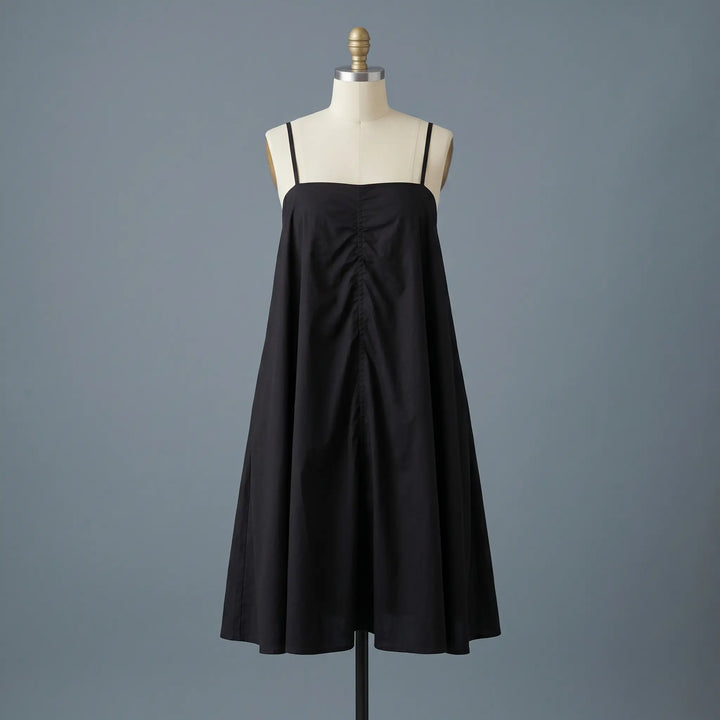 Black 100% cotton A-line mini dress with a square neckline and thin spaghetti straps, featuring a subtle gathered detail, displayed on a mannequin front view.