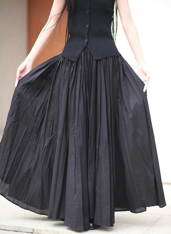 Voluminous black cotton maxi skirt worn by a model, showcasing its full A-line silhouette and gathered elastic waistband with natural creasing.