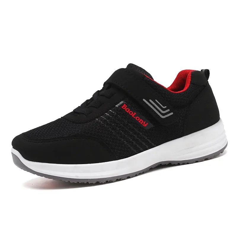 Black breathable mesh sneaker with red accents, featuring a hook-and-loop strap and decorative laces. Includes &