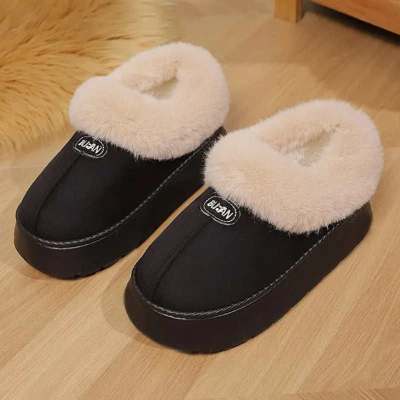 Black mule slippers featuring a plush faux fur trim around the opening and a thick, light brown platform sole, shown from a three-quarter front angle on a wooden floor.