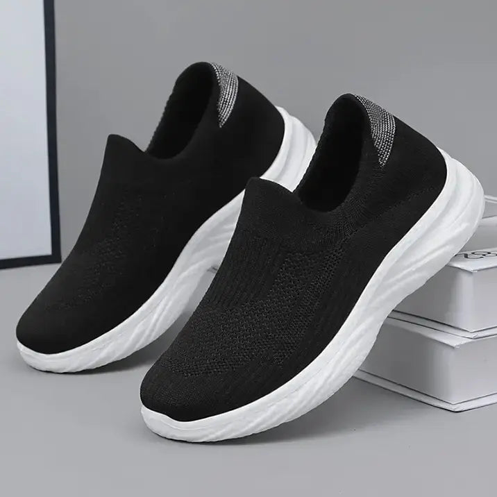 A pair of black Zylpha casual slip-on sneakers with a breathable engineered knit upper and white sculpted cushioned soles, shown from a three-quarter angle.