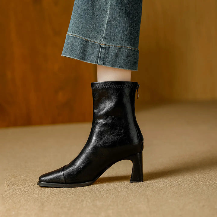 Black leather-look ankle boot with a square toe and a 7cm block heel, shown on a person&