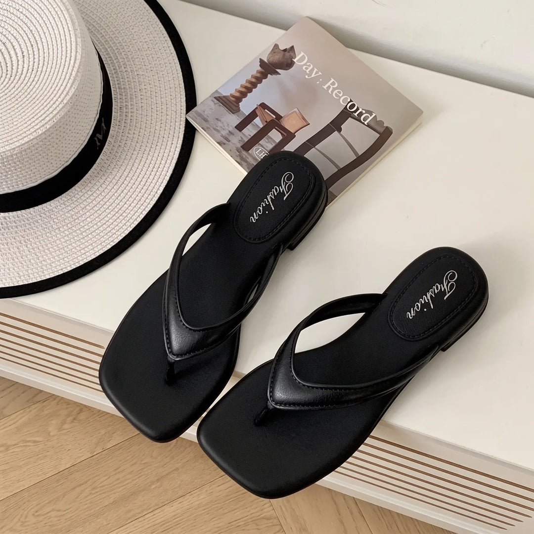 Black square-toe thong sandals with a low wedge heel and embossed &