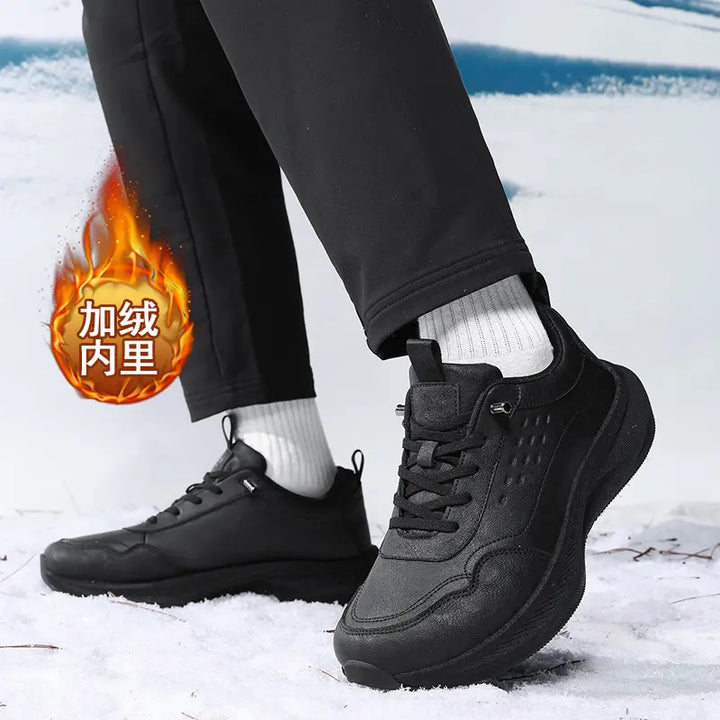 Black wide-fit athletic trainers worn in a snowy environment, featuring a &
