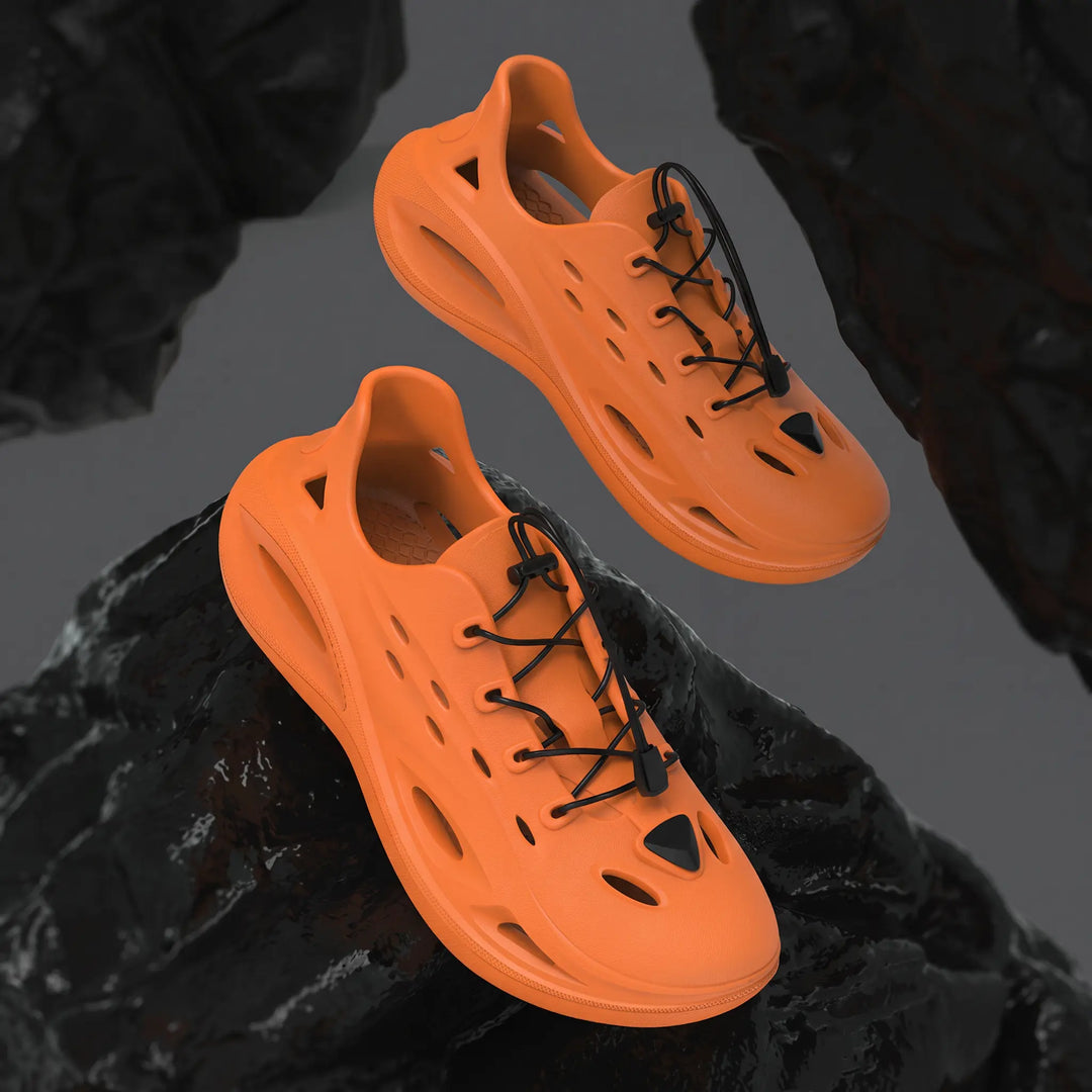 Pair of bright orange Brakko EVA athletic slides with black bungee laces, shown from a three-quarter angle against a dark, textured background. Features a chunky sole and perforated design.