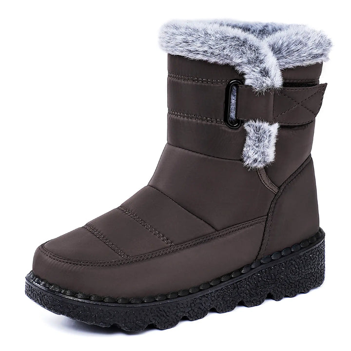 Zyrion brown padded mid-calf winter boot with plush faux fur lining, a decorative ankle strap with buckle, and a thick lugged platform sole, shown from a three-quarter view.
