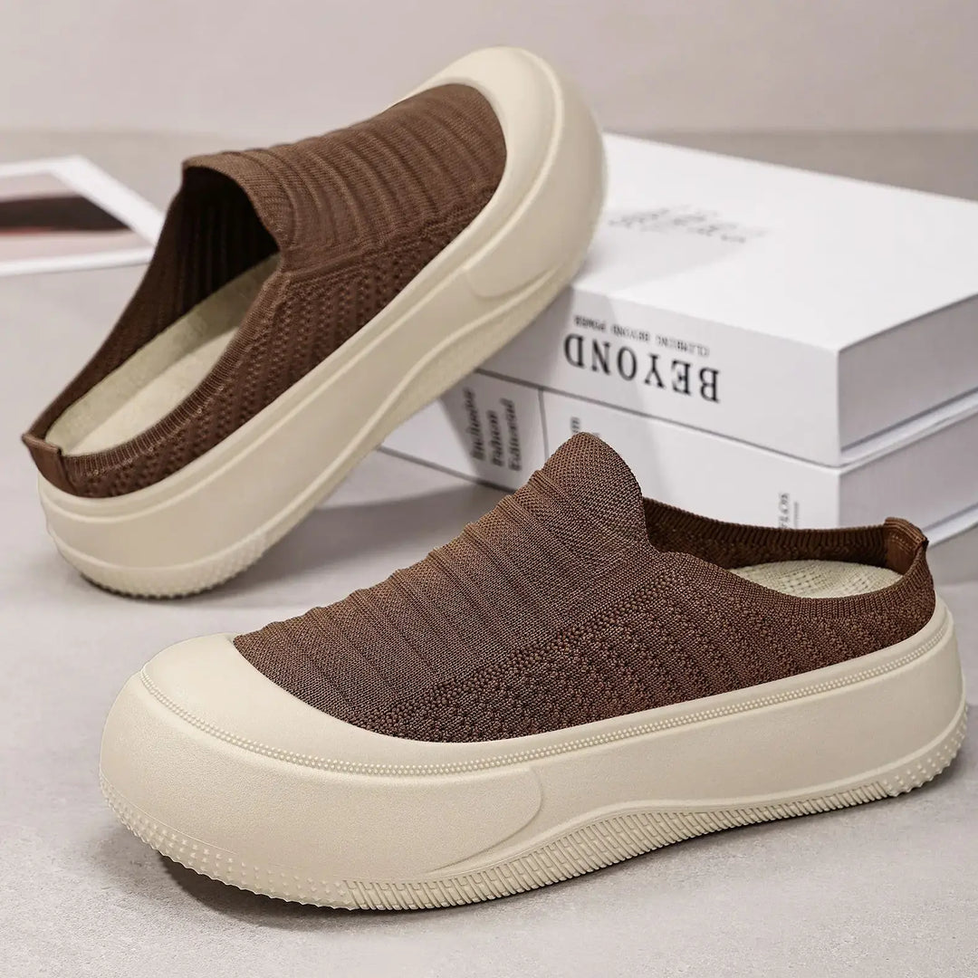 Brown knit slip-on platform mules with a chunky cream sole, showcasing a rounded closed toe and breathable textile upper. This three-quarter view highlights the modern design and comfortable silhouette.