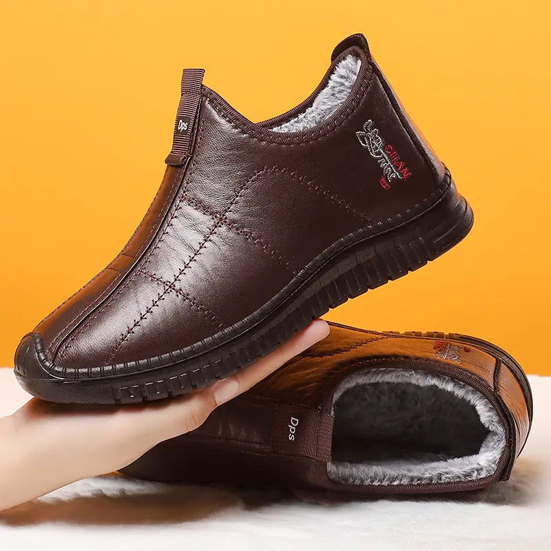 Brown quilted synthetic leather slip-on winter boots lined with fluffy grey faux fur, shown in a three-quarter view with a subtle embroidered emblem on the side.