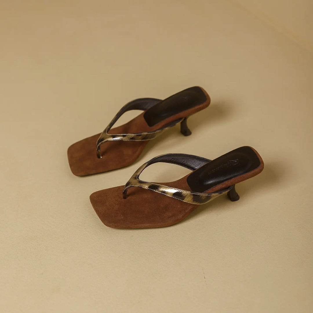 Brown heeled flip-flops with square toe and leopard accent strap, showcasing a three-quarter view on a light beige background.