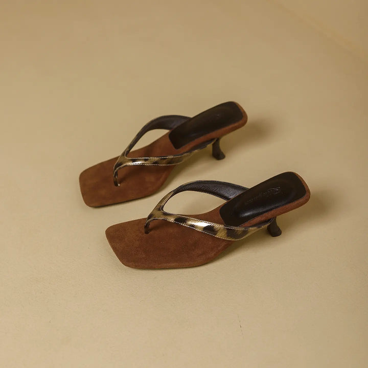 Brown heeled flip-flops with square toe and leopard accent strap, showcasing a three-quarter view on a light beige background.