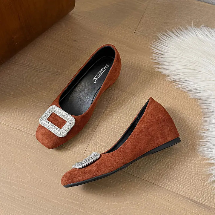Brown suede slip-on wedge flats with a rounded-square toe, featuring a large faceted crystal-embellished square buckle on the vamp.
