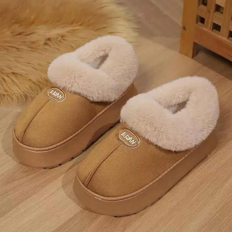 Warm camel suede-like mule slippers with plush cream faux fur lining and an embroidered 'BUAN' logo, shown on a wooden floor with a textured rug.