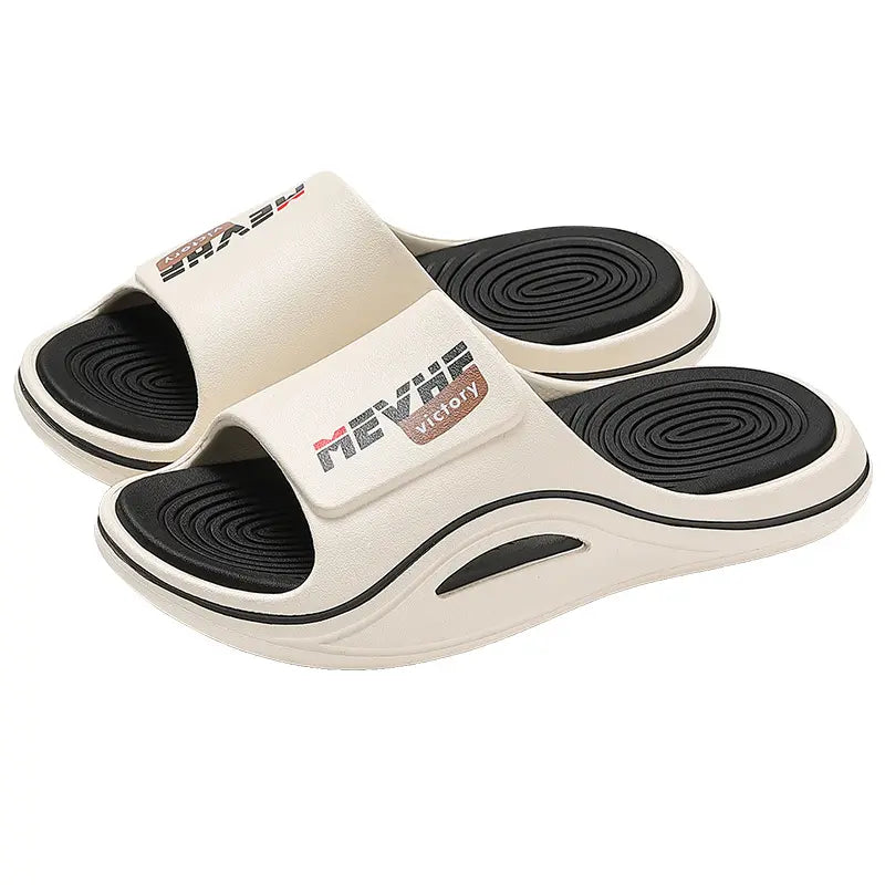 Cream EVA slides with a black textured footbed and thick sculpted sole, featuring the 'MEVRHE VICTORY' logo on the strap.