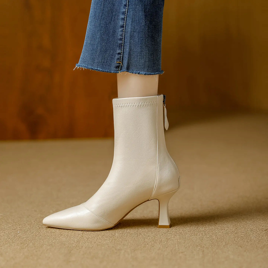 Creamy ivory faux leather pointed-toe ankle boots with a slender stiletto heel and back zipper, styled with cropped denim jeans.