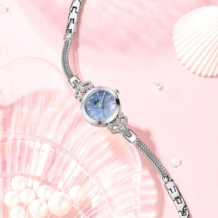 Elegant silver-tone bracelet watch with a delicate blue mother-of-pearl dial, crystal accents on the lugs, and a woven mesh strap.