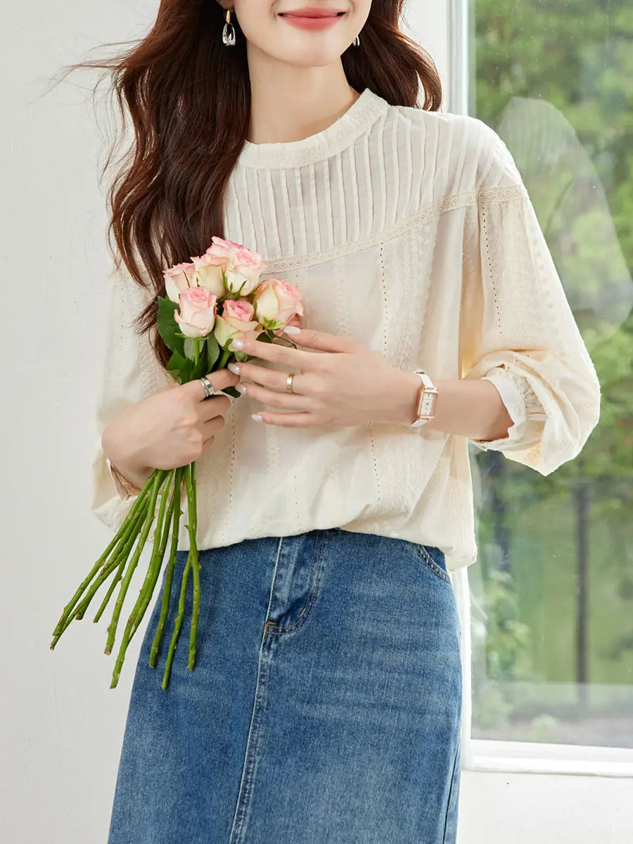 A woman models an off-white embroidered cotton blouse with a gathered round neck and voluminous bishop sleeves, paired with a denim skirt.