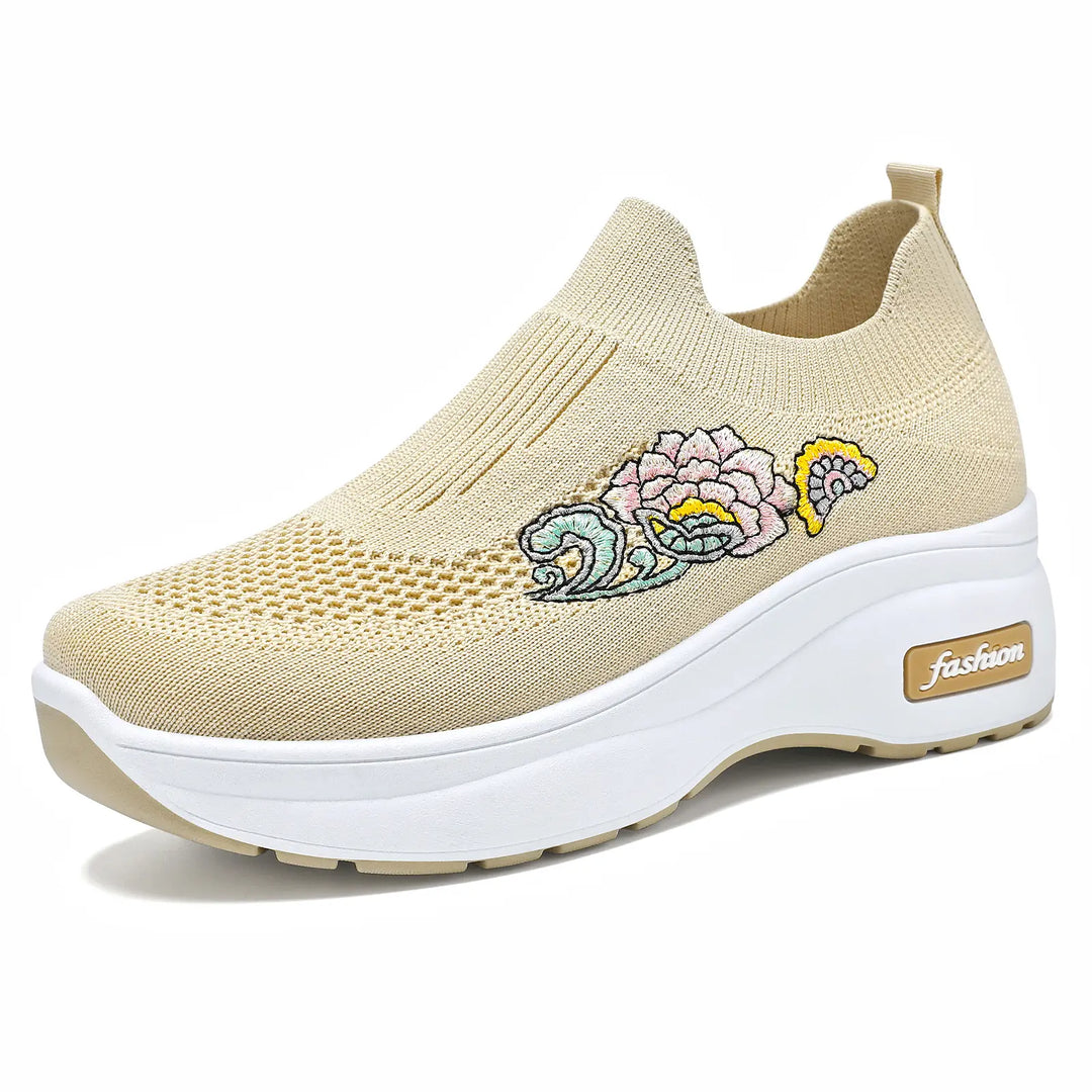 Beige knit slip-on sneaker with colorful floral embroidery on the side and a chunky white platform sole featuring a &