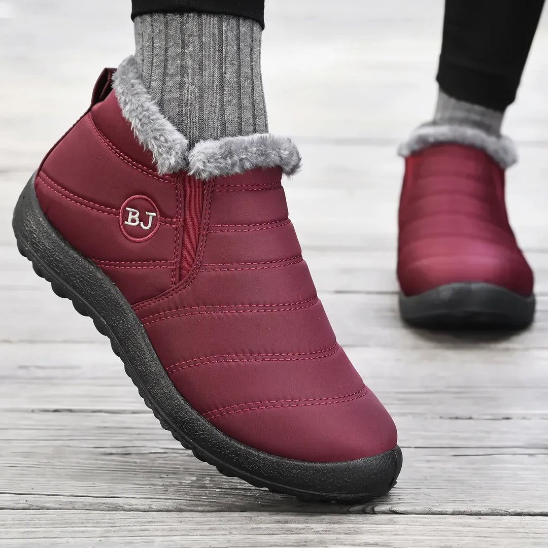Burgundy Faelan waterproof ankle boots with plush light grey faux fur trim and horizontal quilting, shown on a person&