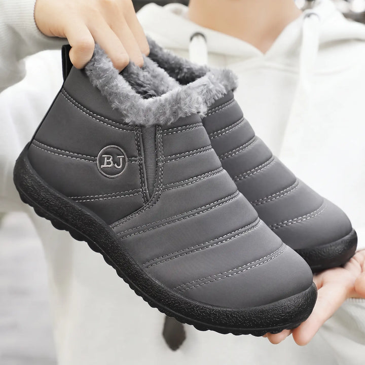Grey Faelan waterproof winter ankle boots featuring a plush faux fur lining, quilted nylon upper, elasticated side panels, and a black rubber sole.