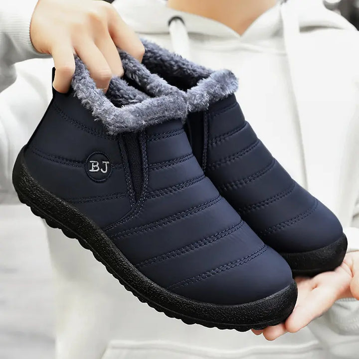 Pair of matte navy blue quilted winter ankle boots with plush light grey faux fur lining and &