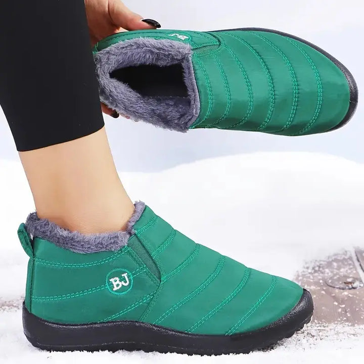 Green quilted waterproof winter ankle boots with grey faux fur lining shown on a model&