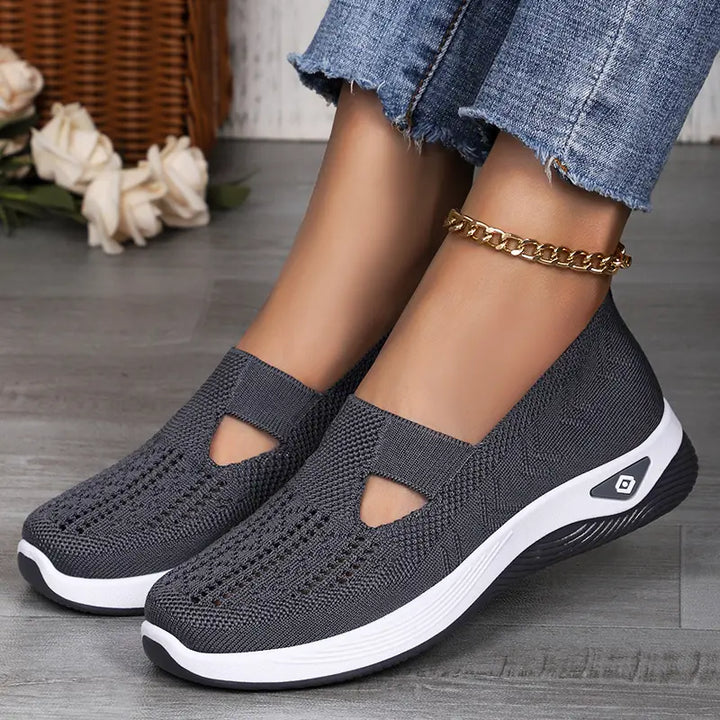 Grey breathable mesh slip-on trainers for women, styled with blue denim jeans and a gold anklet, showcasing comfort and casual style.