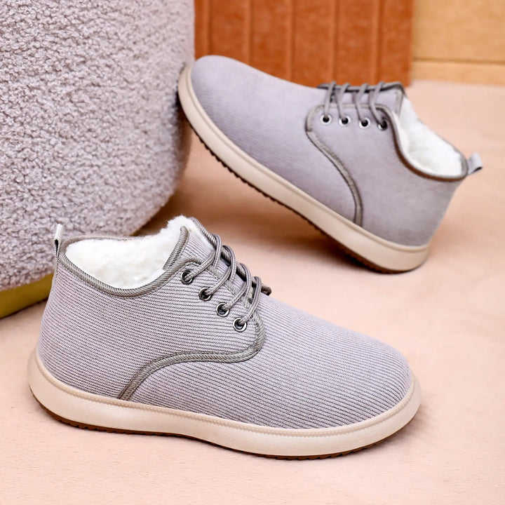 Two grey casual winter boots with plush faux fur lining and lace-up closure, presented at a three-quarter angle against a soft, textured studio background.