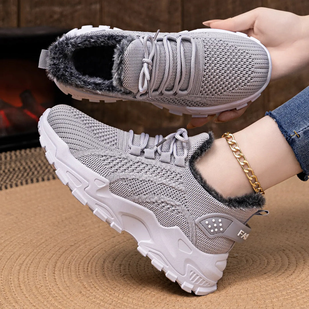 Grey knit ankle boots with plush faux fur lining and a chunky white platform sole, shown worn on a foot with a gold anklet.