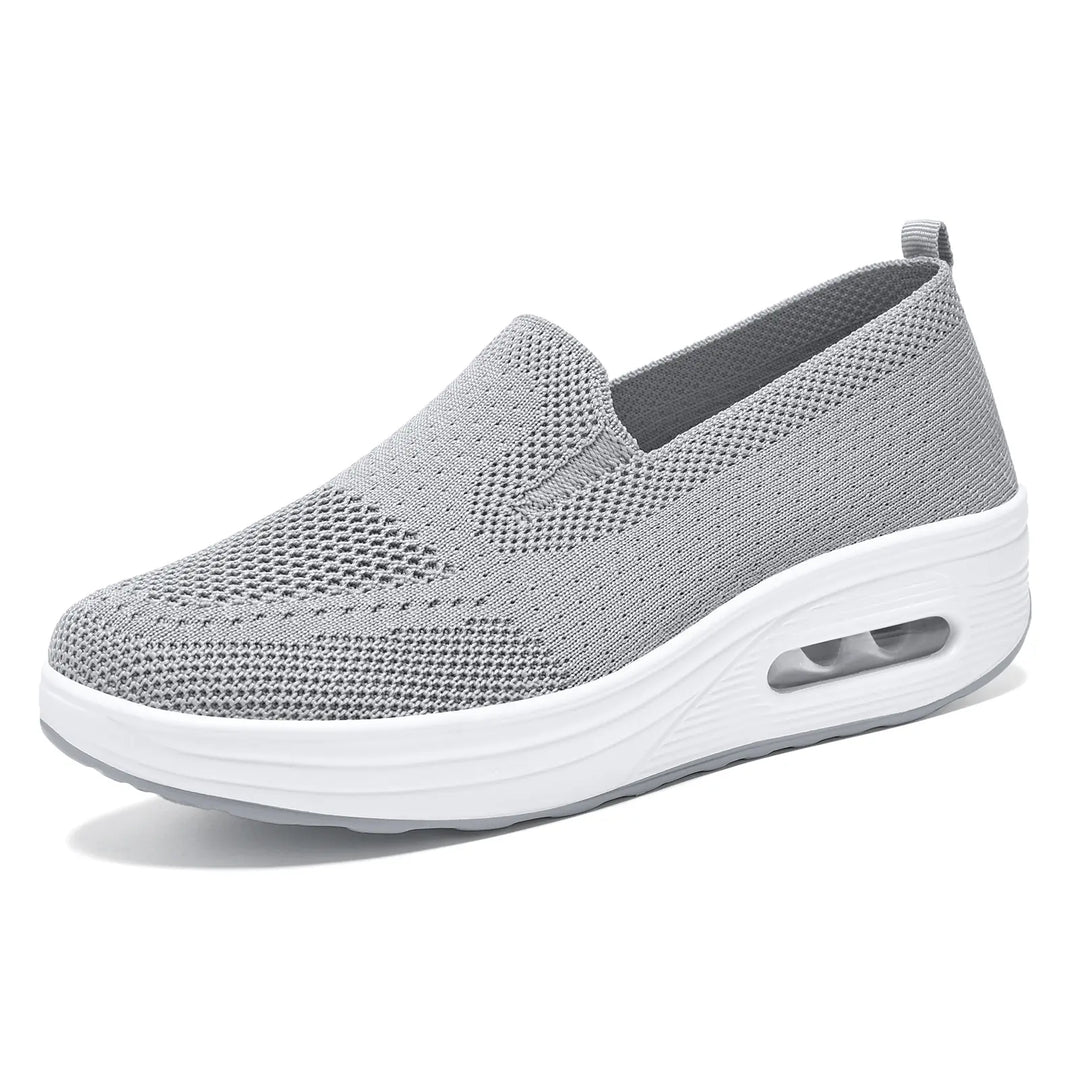 Grey slip-on sneaker with a breathable knit upper, white platform sole, and visible air cushion heel, shown from a three-quarter angle on a white background.