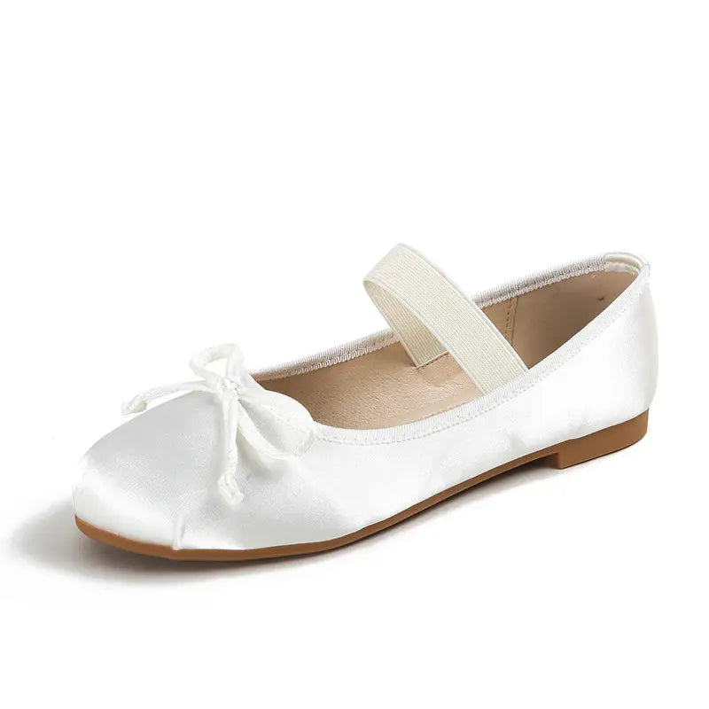 Ivory white satin ballet flats featuring a delicate bow and an elastic instep strap, presented from a three-quarter view on a white studio background.