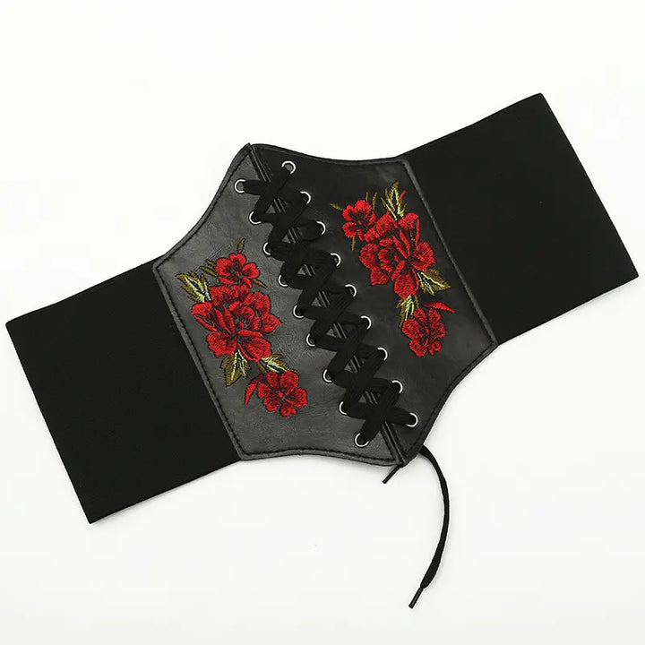 Kaelan corset-style wide belt in black faux leather with vibrant red floral embroidery and lace-up front closure.