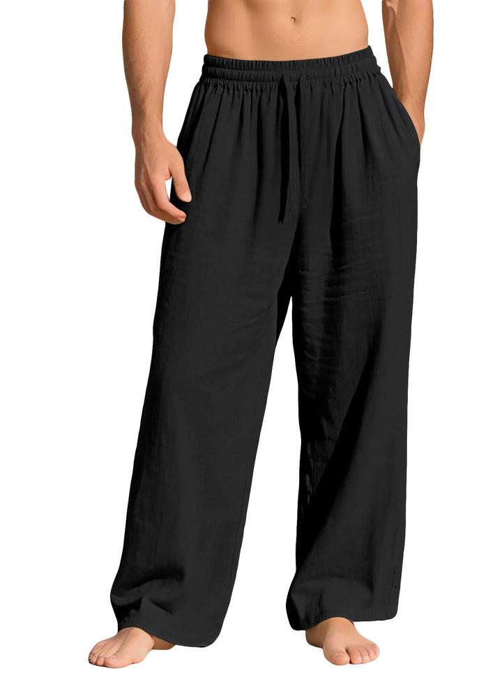 Black relaxed-fit linen-blend trousers for men, featuring a wide-leg silhouette, elasticated waistband with drawstring, and side pockets, shown on a model against a clean white background.