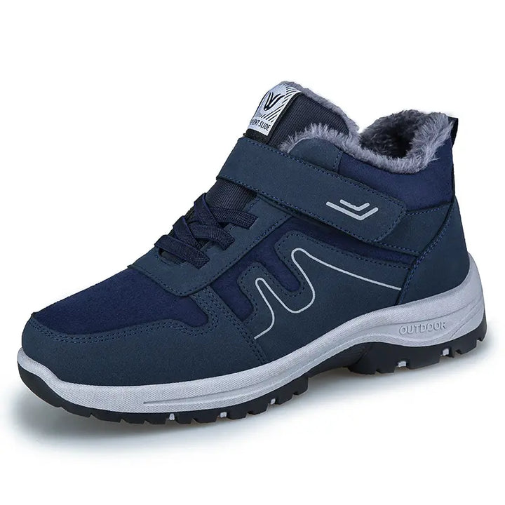 A pair of dark blue fleece-lined ankle boots with a hook-and-loop strap, traditional laces, and a wavy side design, presented from a three-quarter view on a clean white background.
