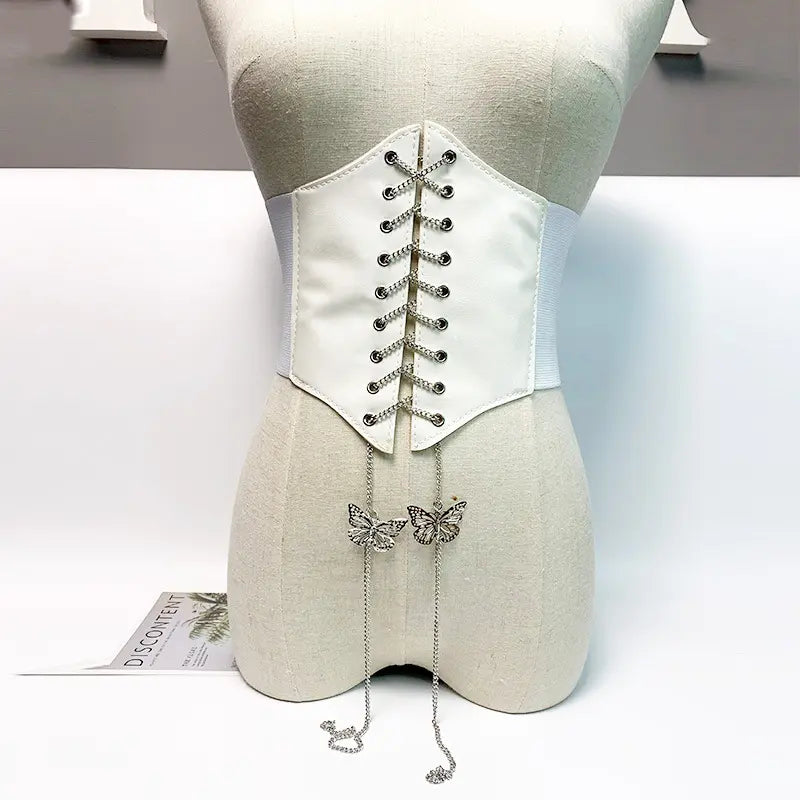 White Kaelan corset belt with silver chain lace-up and dangling butterfly charms, displayed on a mannequin front view.