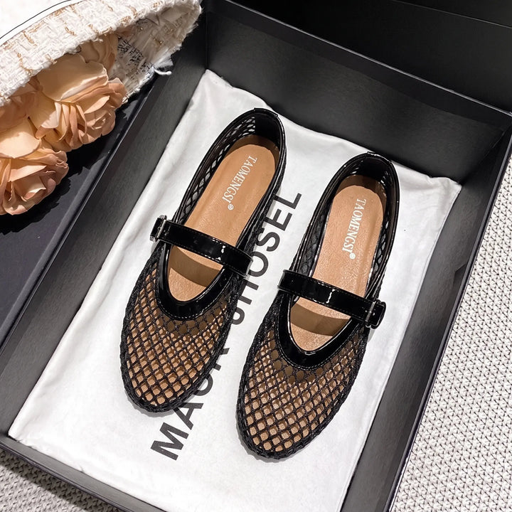 A pair of Kaelen black mesh Mary Jane ballet flats with glossy patent trim and adjustable buckle straps, shown in a product box.