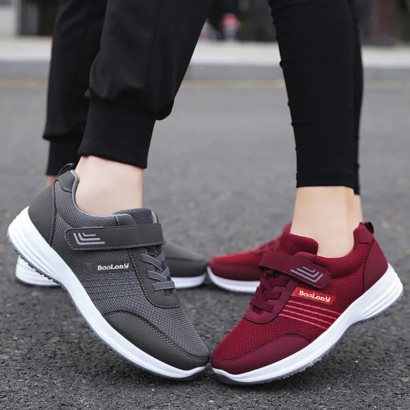 Two pairs of Kaelen breathable mesh sneakers worn by individuals, one burgundy and one dark grey, featuring dual closure systems with hook-and-loop straps.