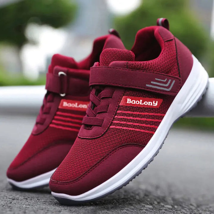 Burgundy Kaelen breathable mesh sneakers with a dual hook-and-loop strap and decorative laces, shown from a three-quarter angle on a studio background. Features white midsole and grey rubber outsole.